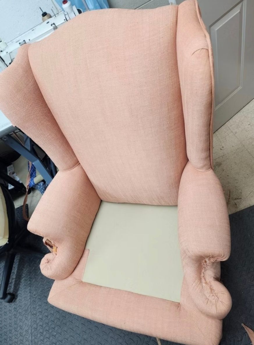 A pink chair with a white cushion is sitting on the floor.