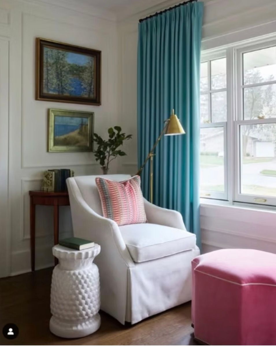 A living room with a white chair and pink ottoman