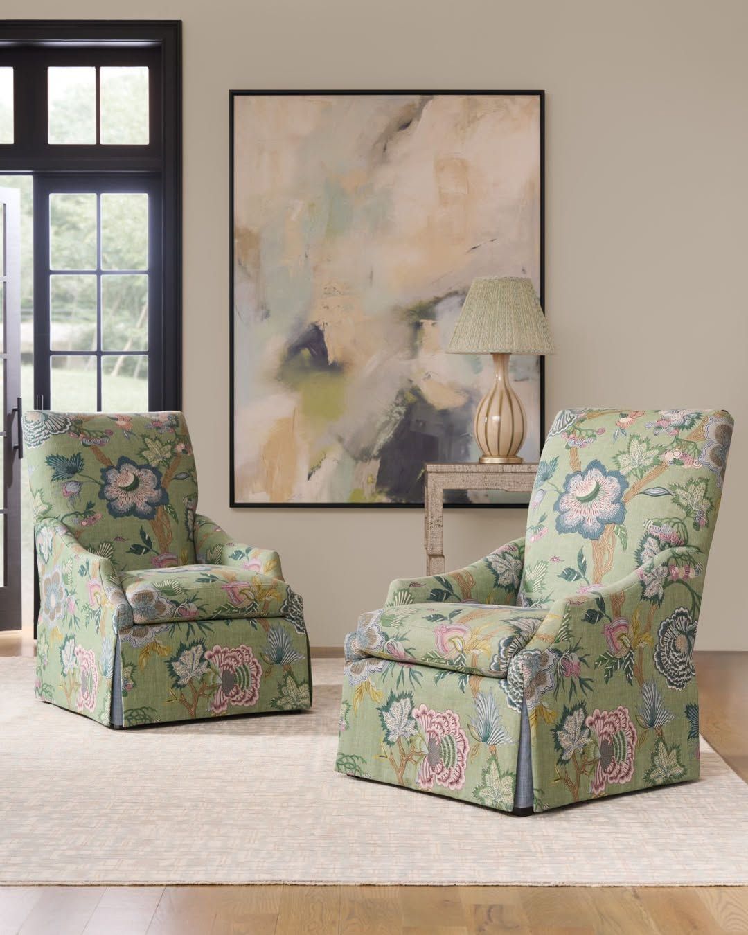 A living room with two chairs , a lamp and a painting on the wall.