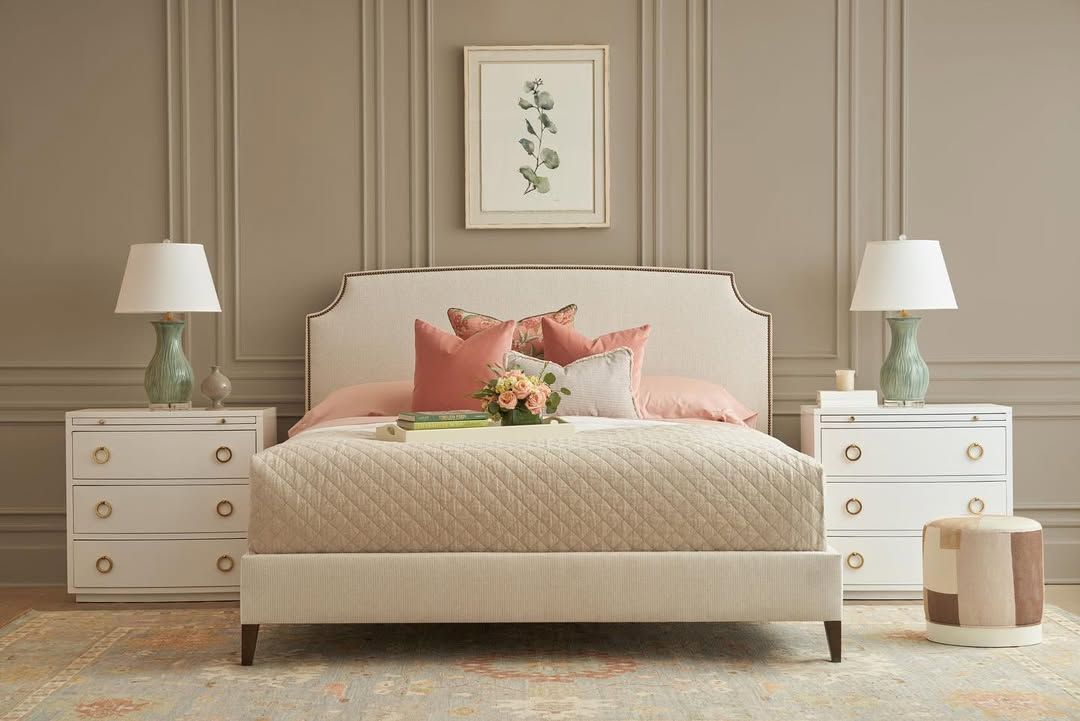 A bedroom with a bed , nightstands , lamps and a picture on the wall.