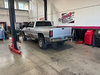 Silver pickup truck in a garage beside a red car lift and tool cabinets