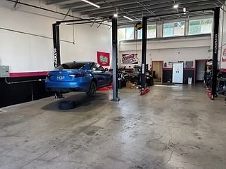 Auto shop interior with a blue car on a lift and several cars parked in a service bay