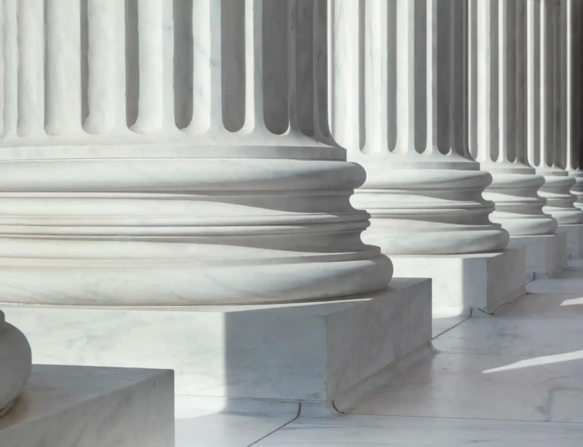 White marble courthouse columns lined along a sunlit walkway.