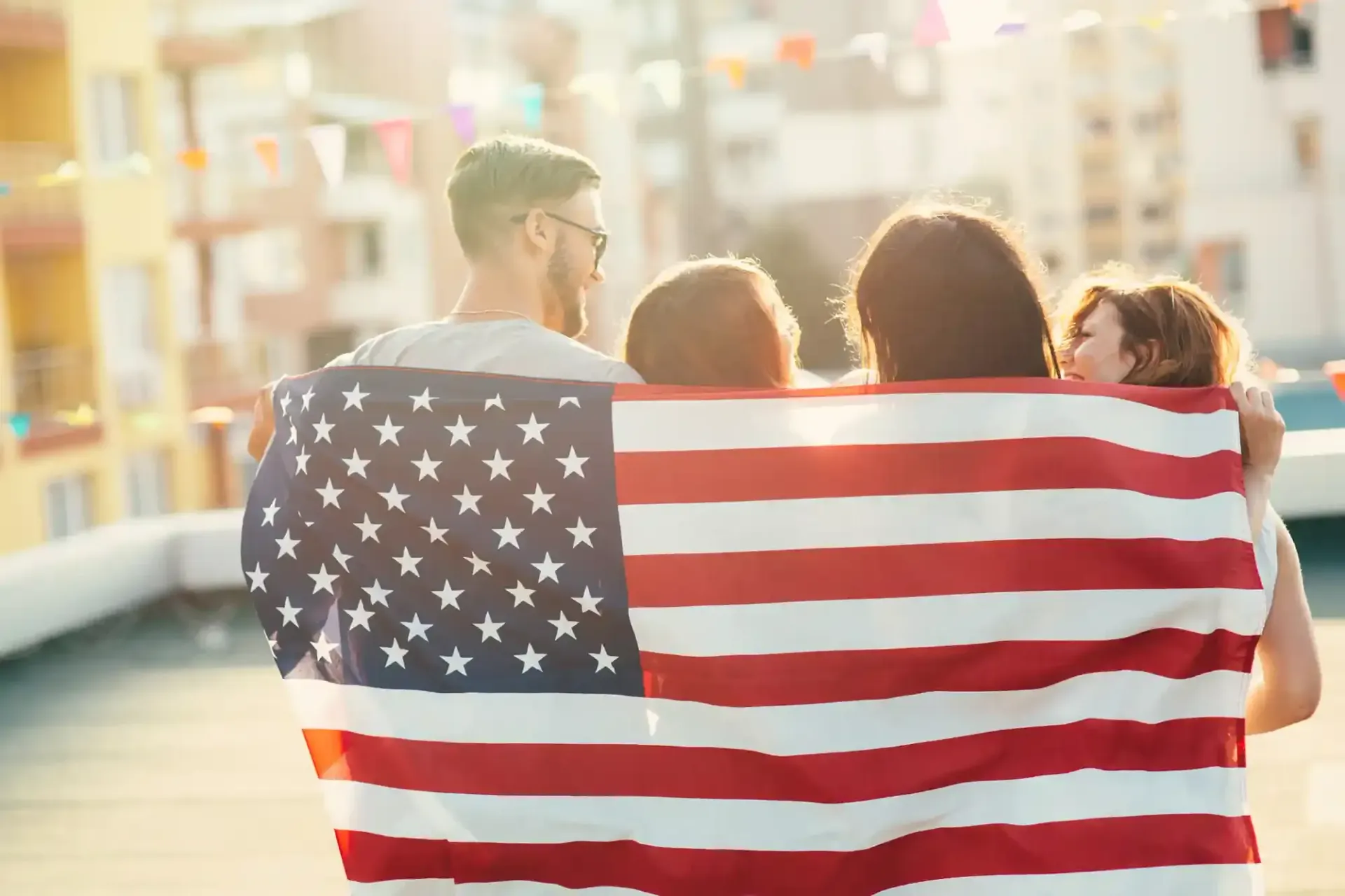 Three people walk away draped in an American flag on a city street.