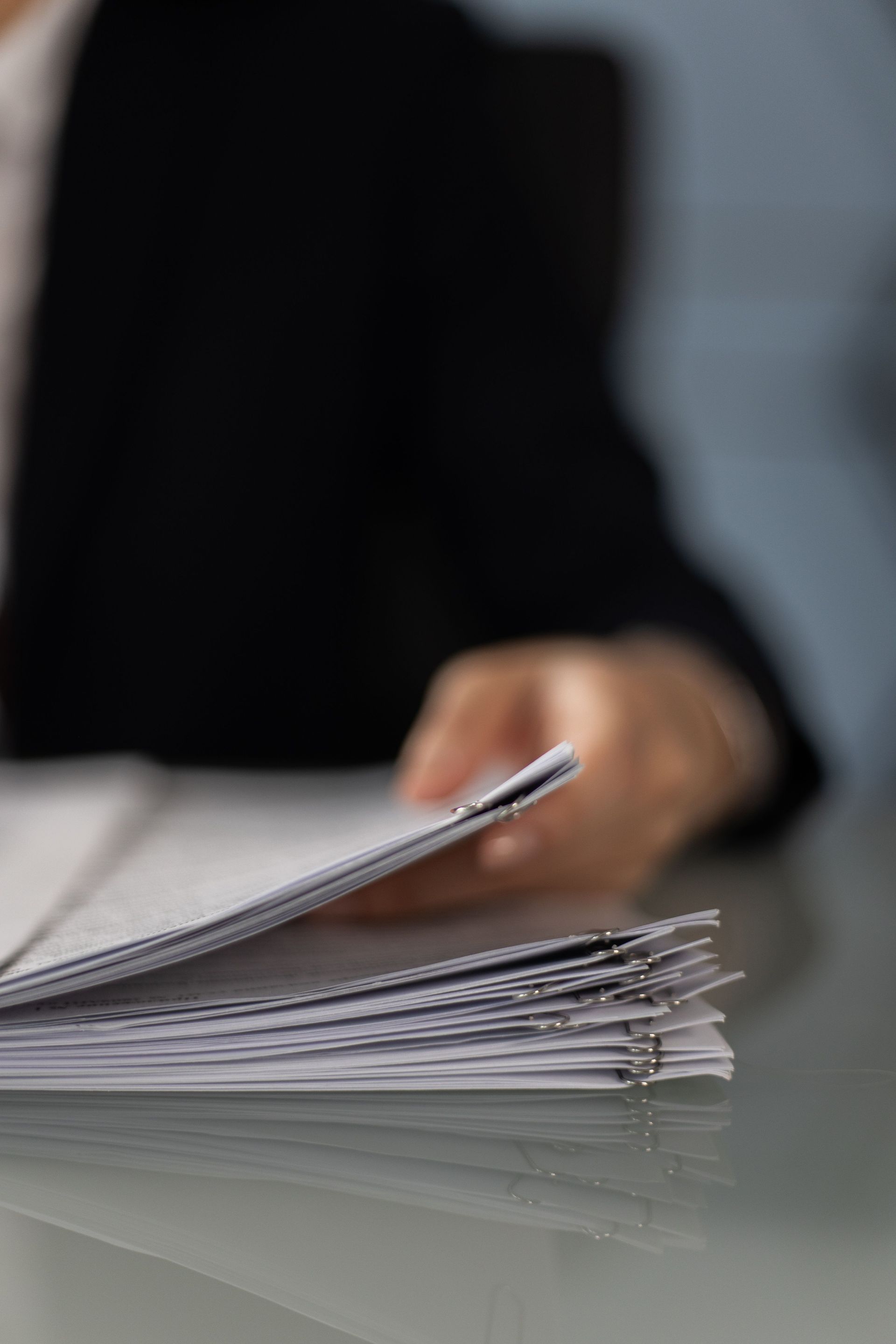 Hand flipping through a stack of papers on a desk