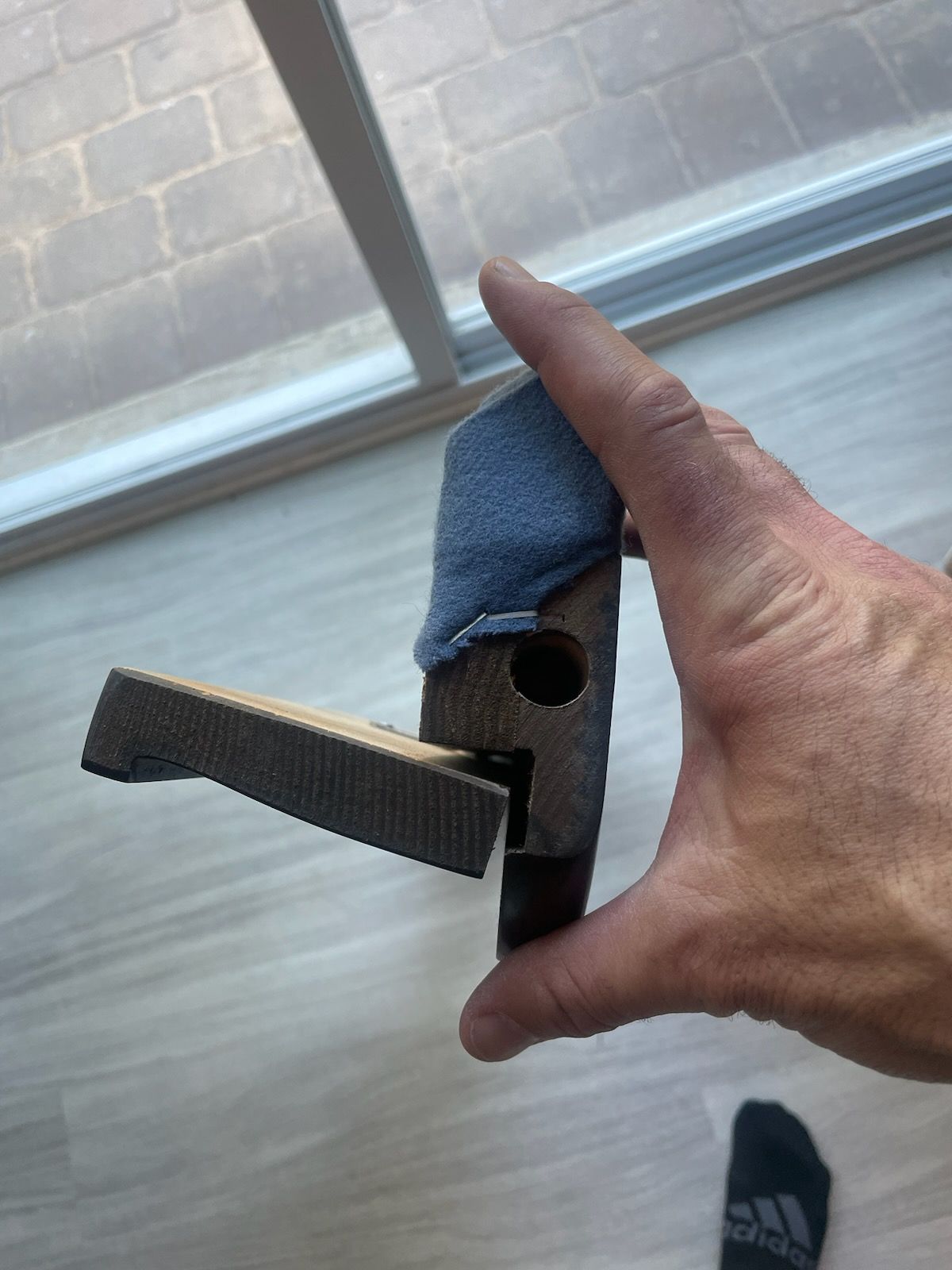 Hand holding a small blue fabric pouch with a metal latch near a window.