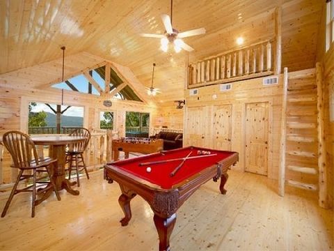 Rustic log cabin game room with a red pool table, bar stools, and wooden loft ceiling