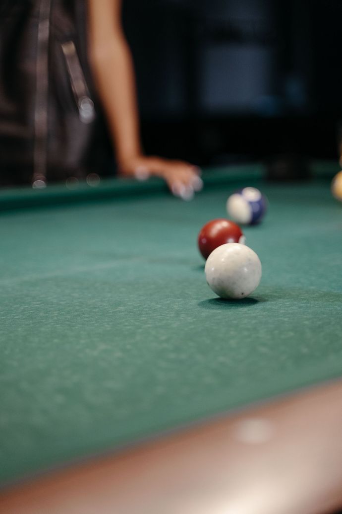 Pool balls on a green table with a player’s arm blurred in the background