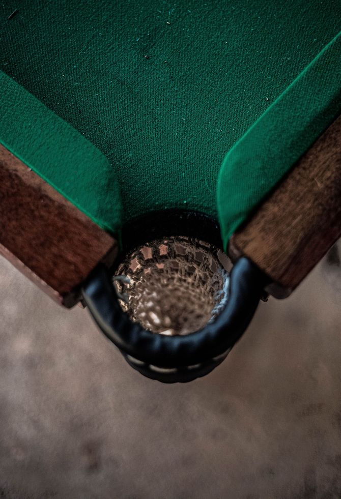 Close-up of a green fabric chair corner with a dark brown frame and round metal hinge connector