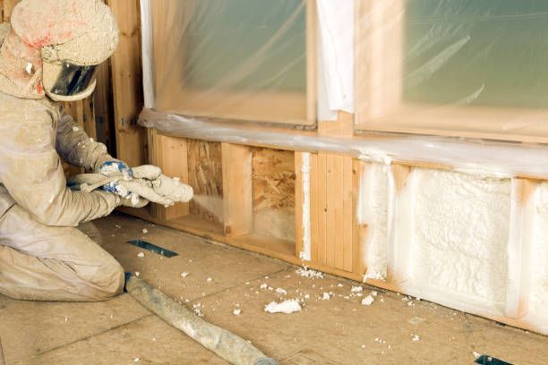 Applying foam insulation along a window frame.