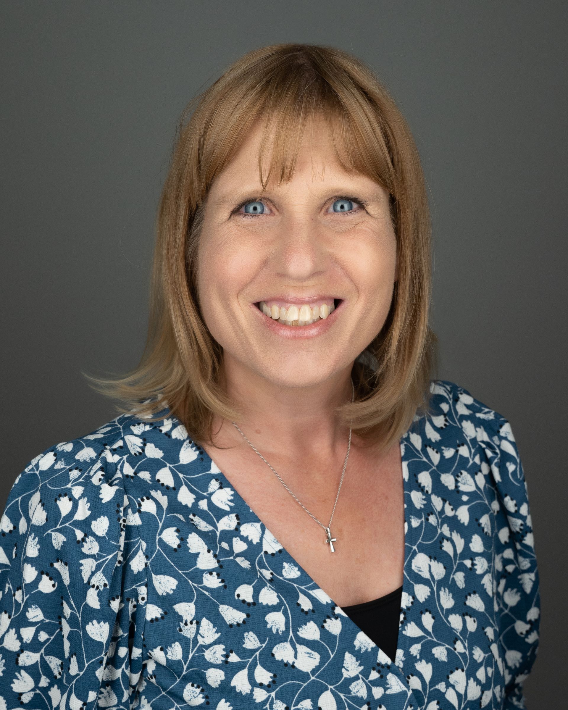 Lisalynne Quinn in a blue patterned blouse against a gray background