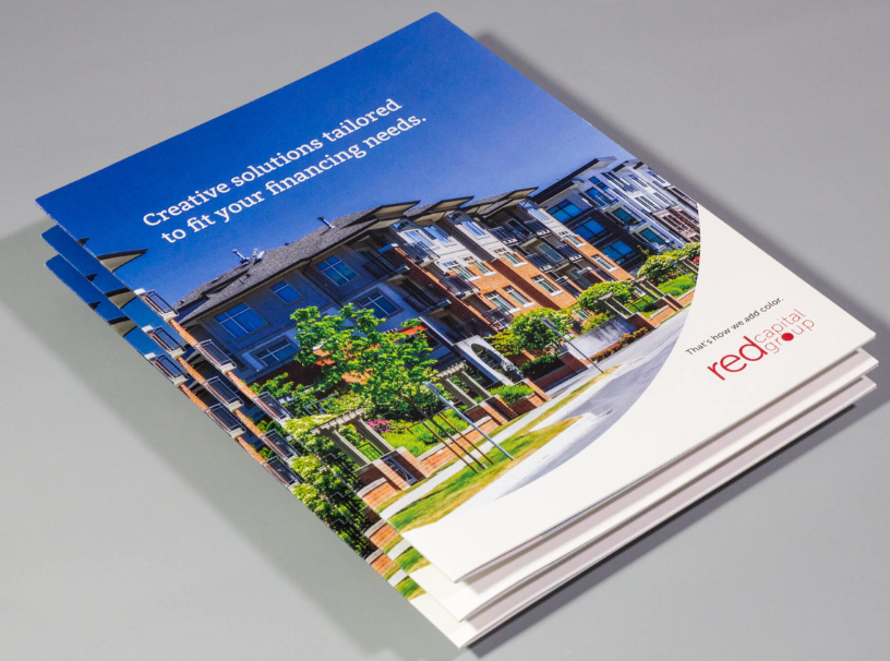 Stack of brochures with a blue and white cover featuring a building and the 