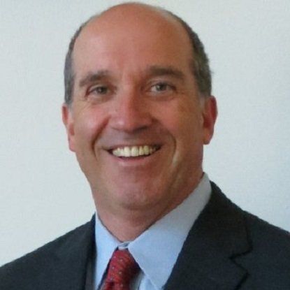 Man in suit smiling, looking at the camera.