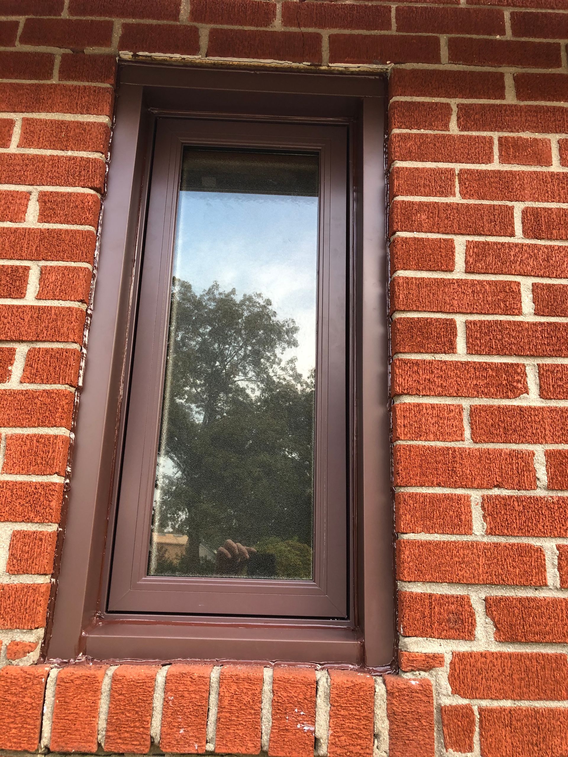 A window on a brick wall with a brown frame