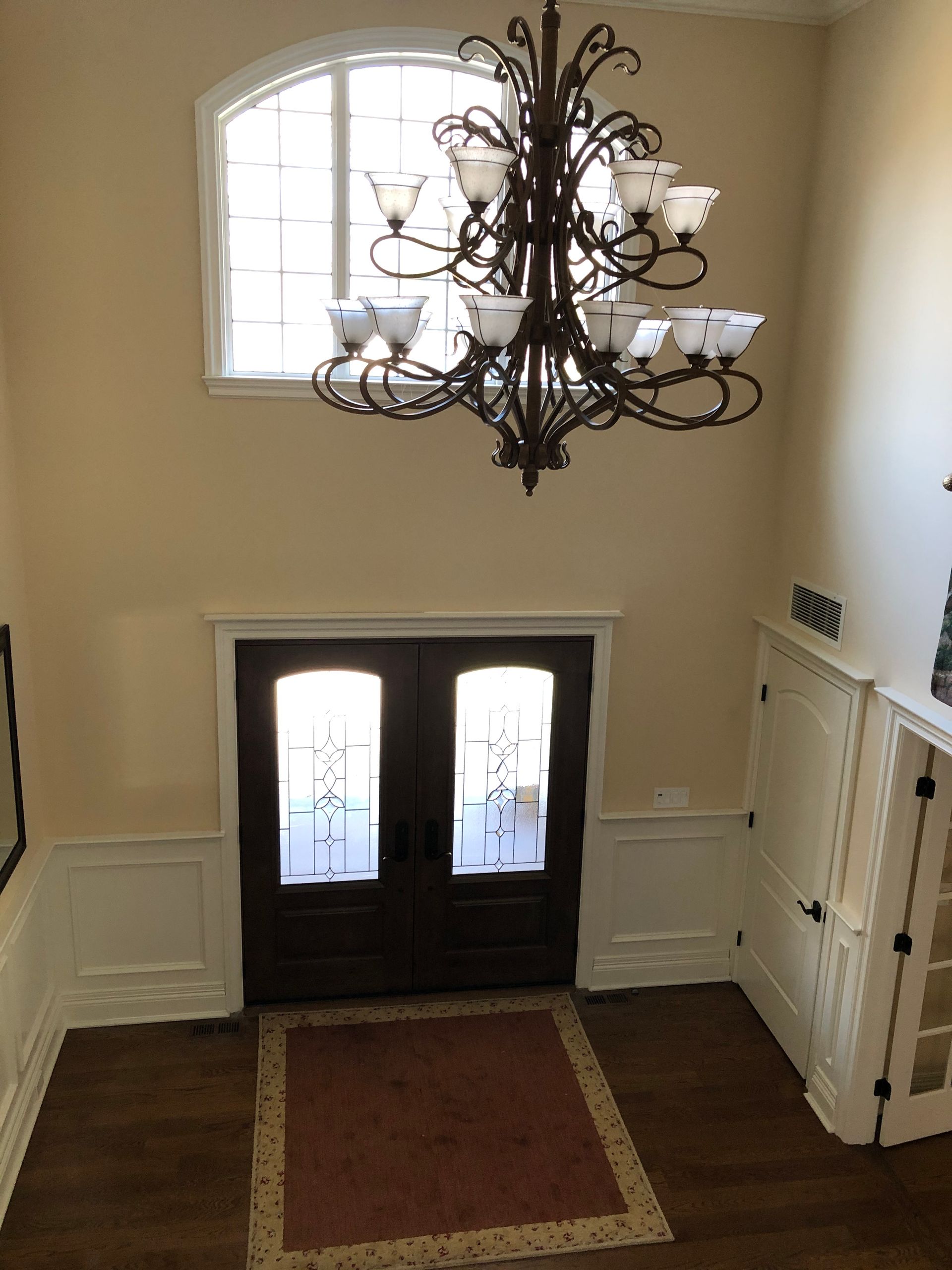 A chandelier is hanging from the ceiling above a door in a hallway.