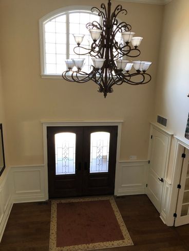 A chandelier is hanging from the ceiling above a door in a hallway.