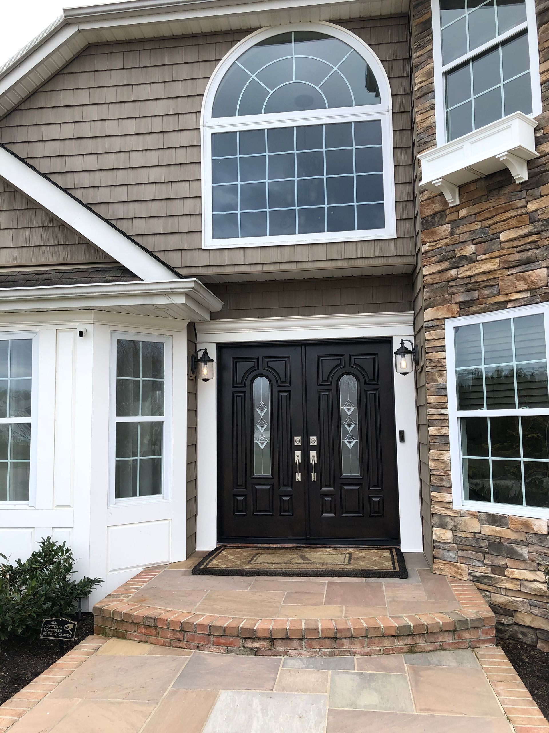 A large house with a black door and a stone wall.