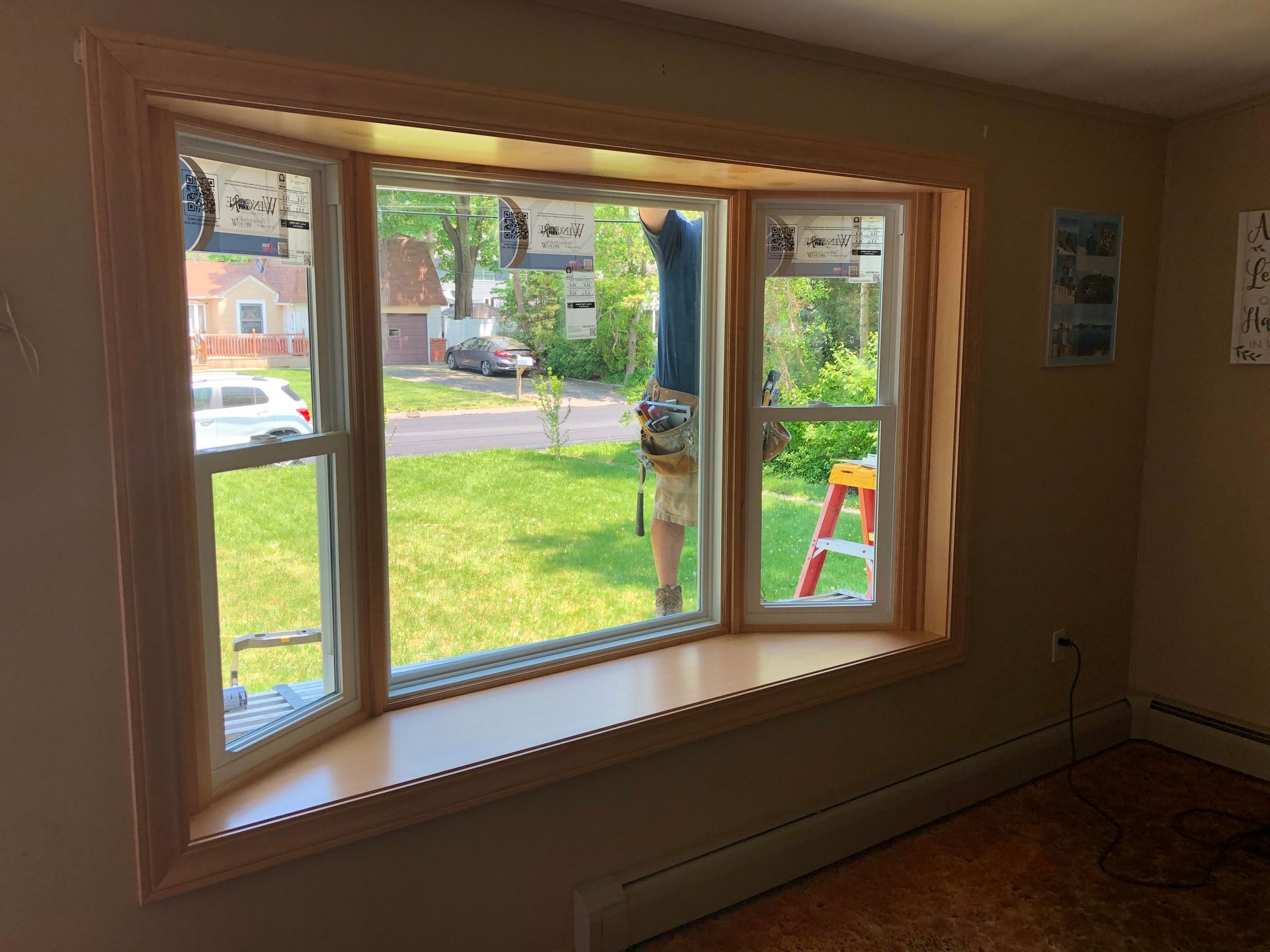 A man is working on a bay window in a living room.