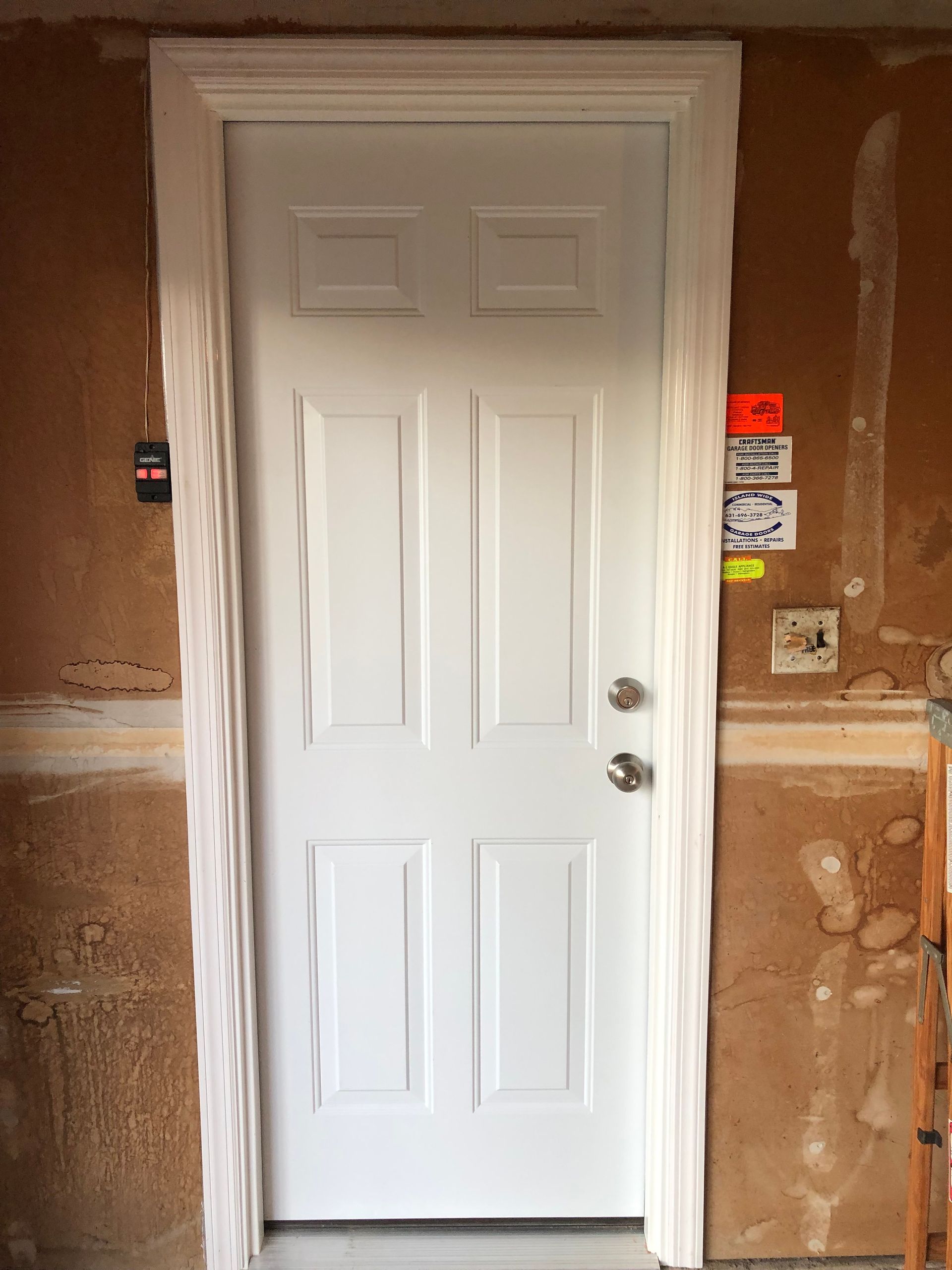 A white door is sitting in a room next to a wall.