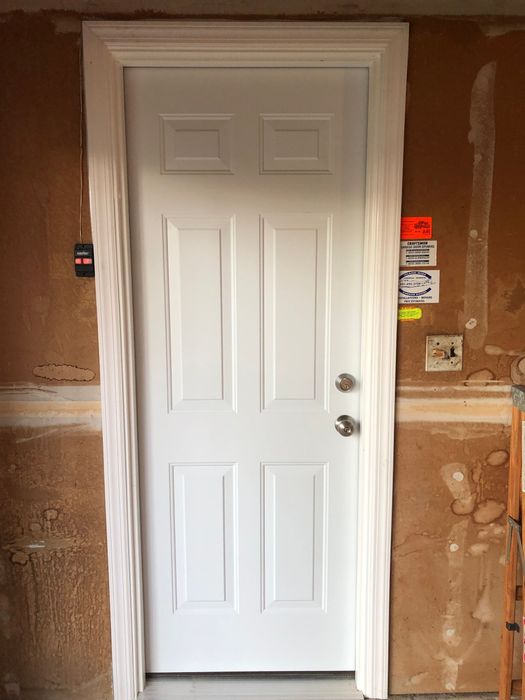A white door is sitting in a room next to a wall.
