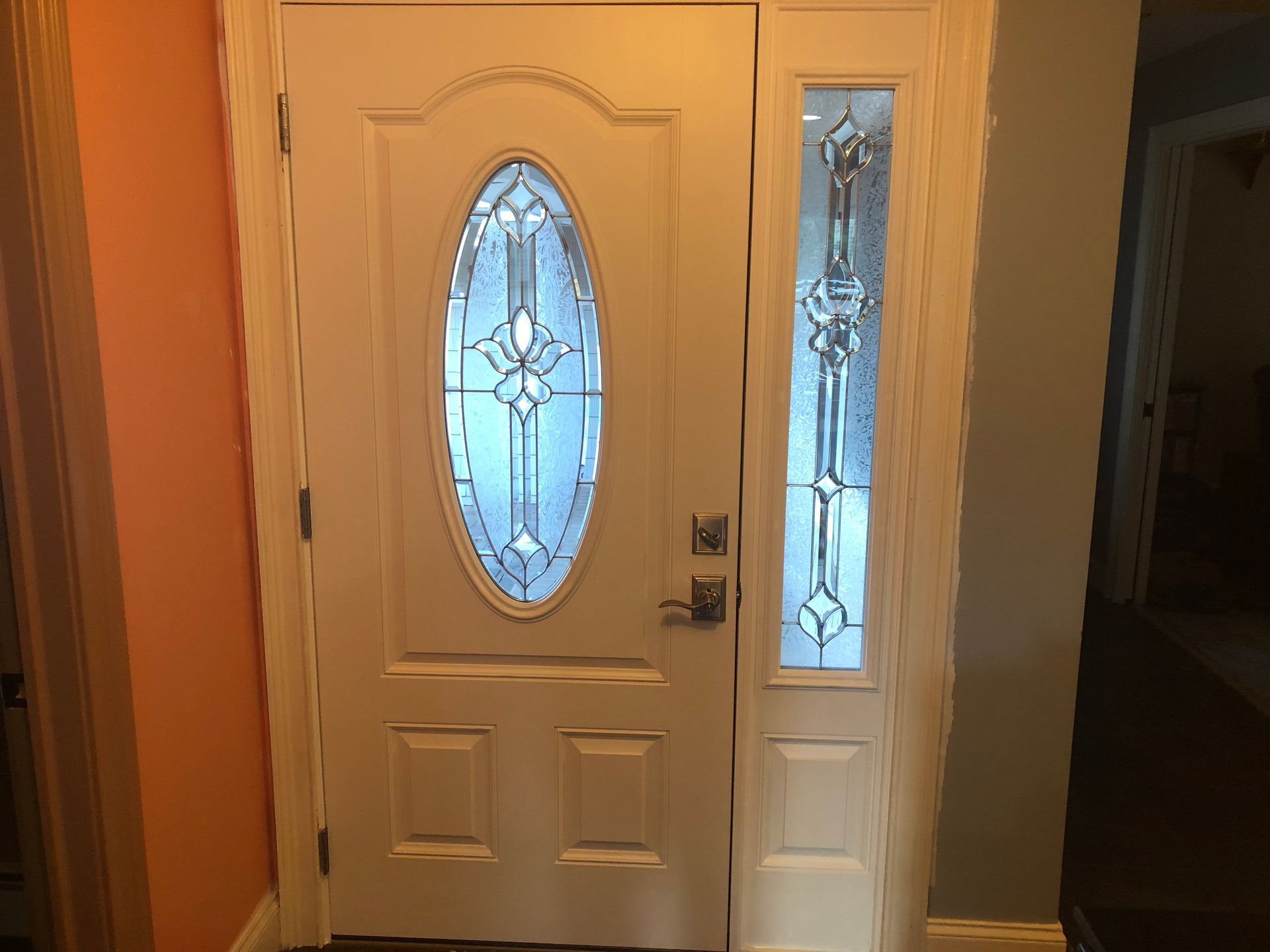A white door with a stained glass window in a hallway.