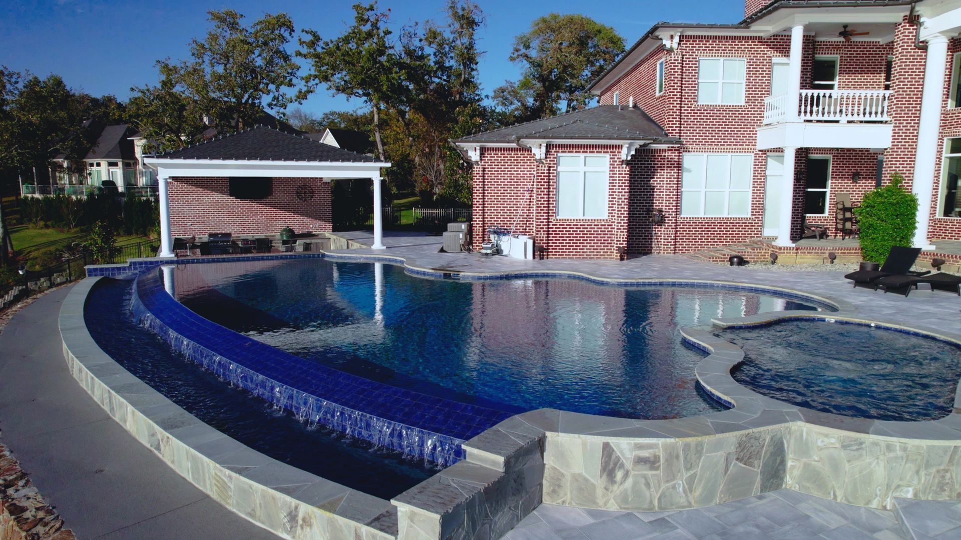 A large brick house with a large swimming pool in front of it