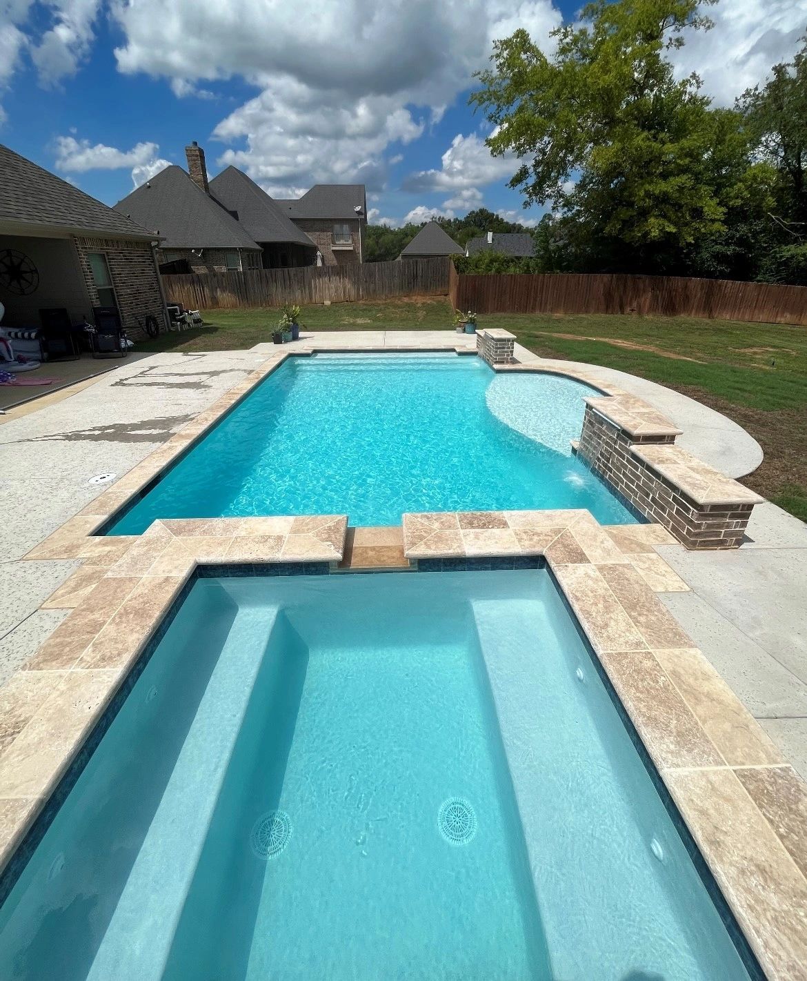 A large swimming pool with stairs leading to it in a backyard.