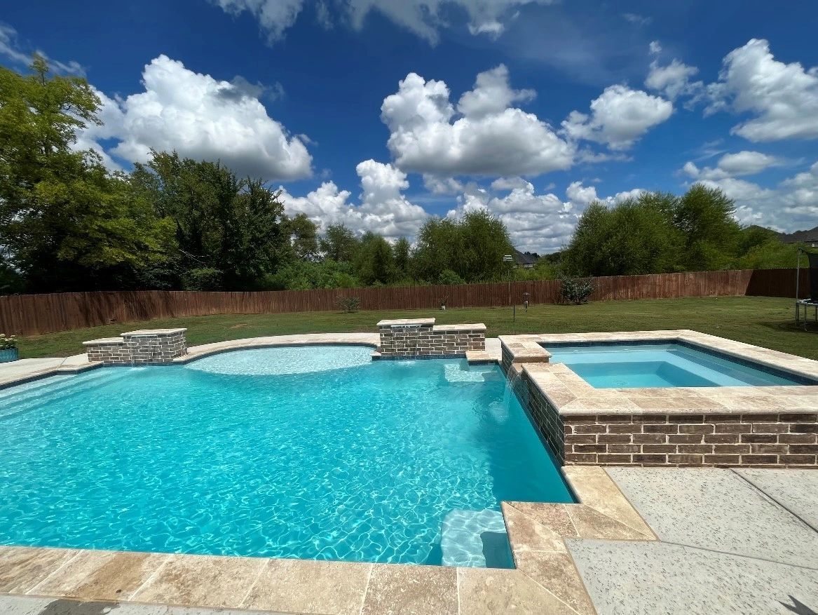 A large swimming pool with a hot tub in the backyard