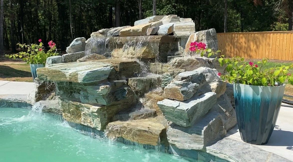 There is a waterfall in the middle of a swimming pool.