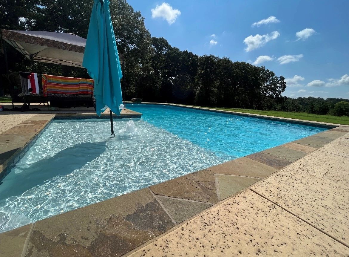 A large swimming pool with a blue umbrella in the middle