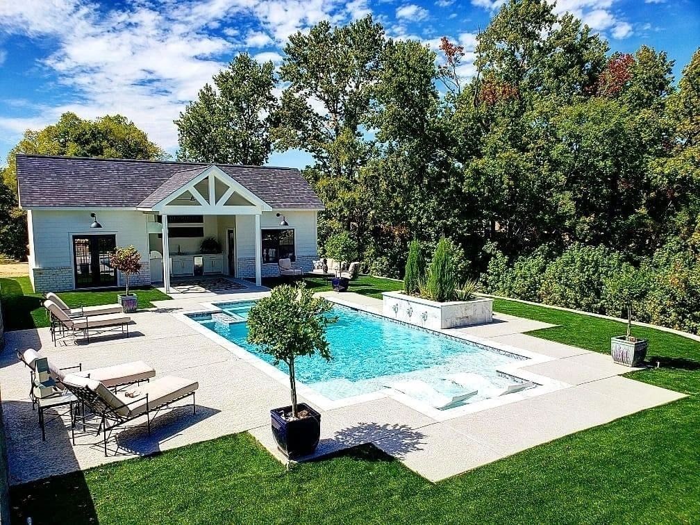 There is a large swimming pool in the backyard of a house.