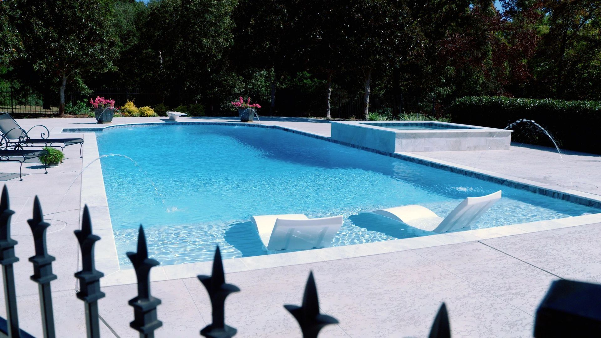 A large swimming pool is behind a wrought iron fence