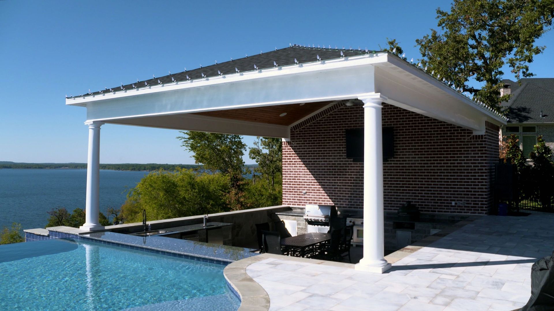A pavilion overlooking a swimming pool with a view of a lake