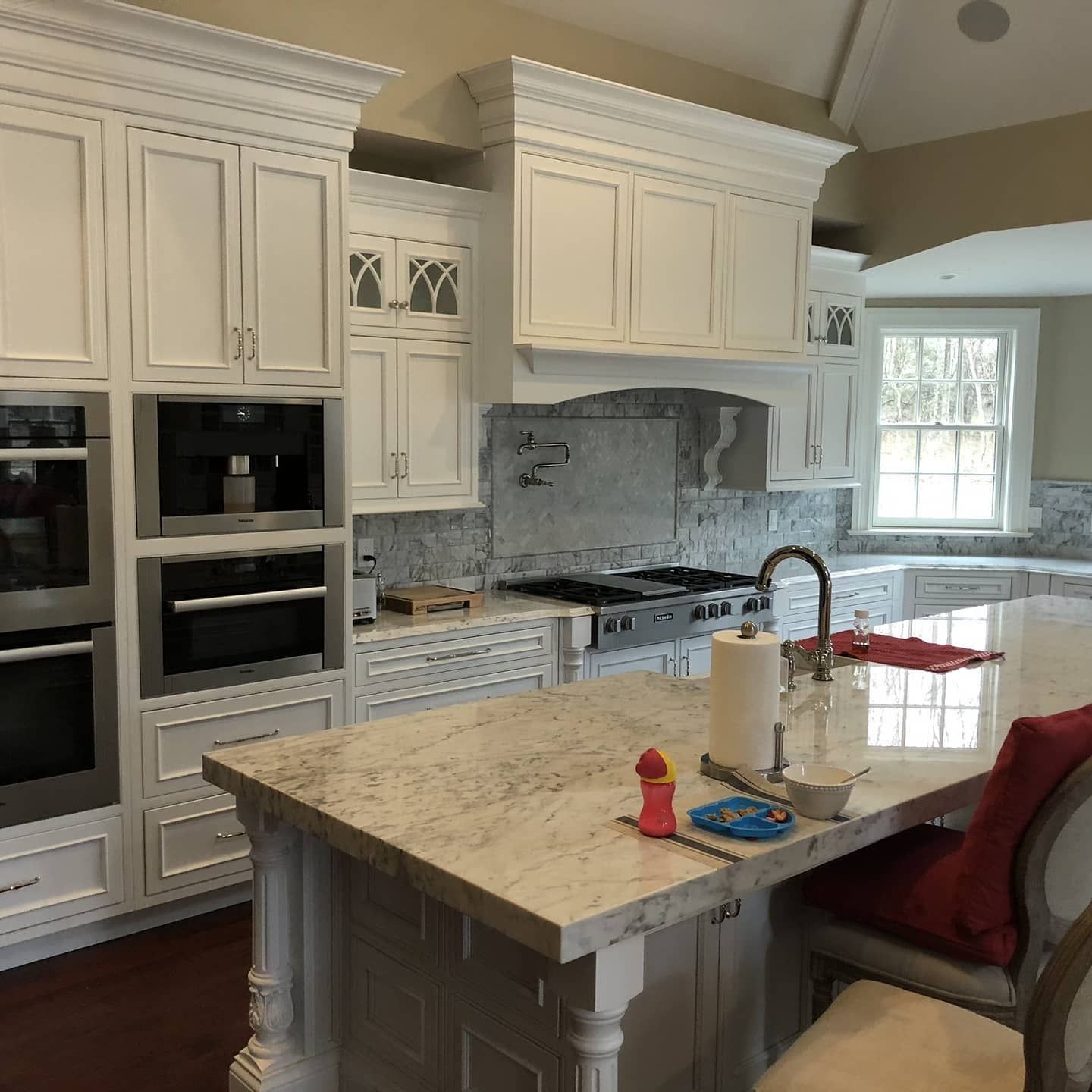 White kitchen with granite countertops, stainless steel appliances, and island with seating.