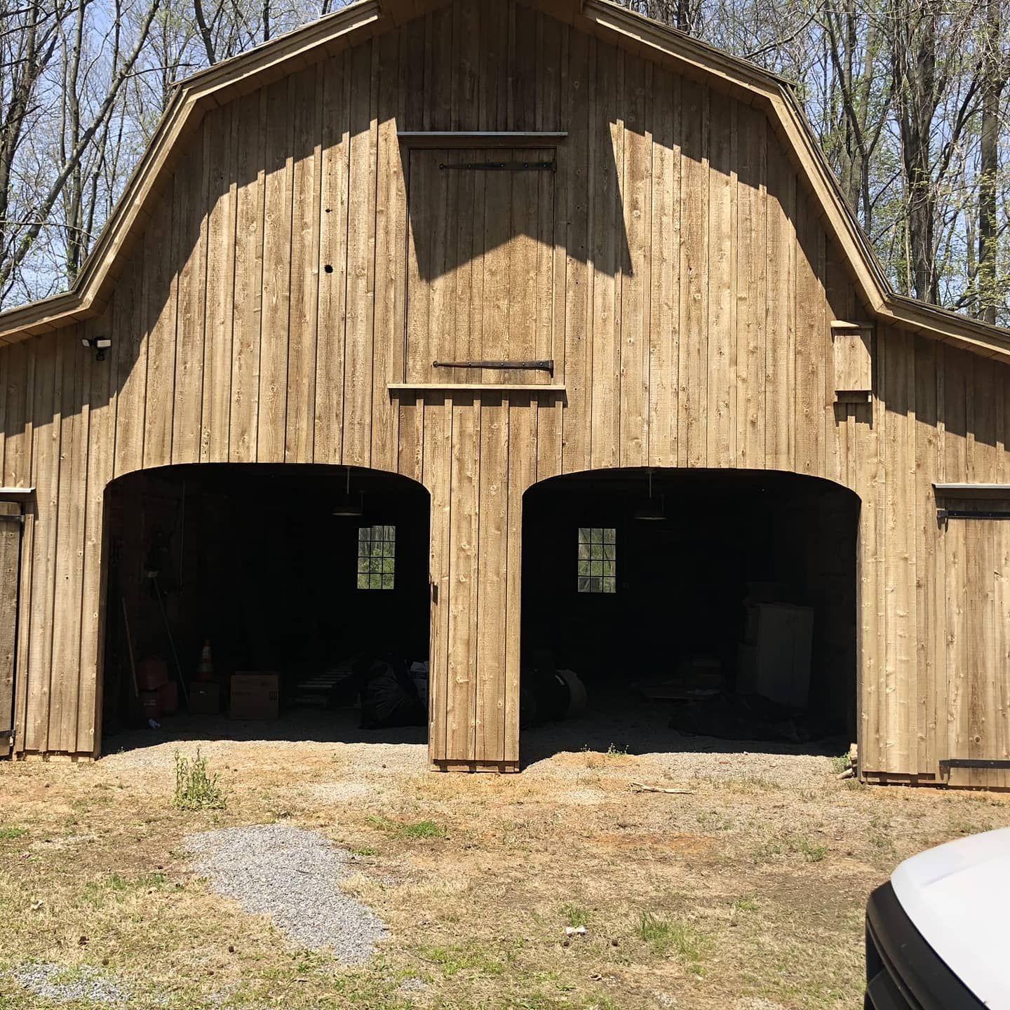 Wooden barn with two arched openings, windows, and closed doors.