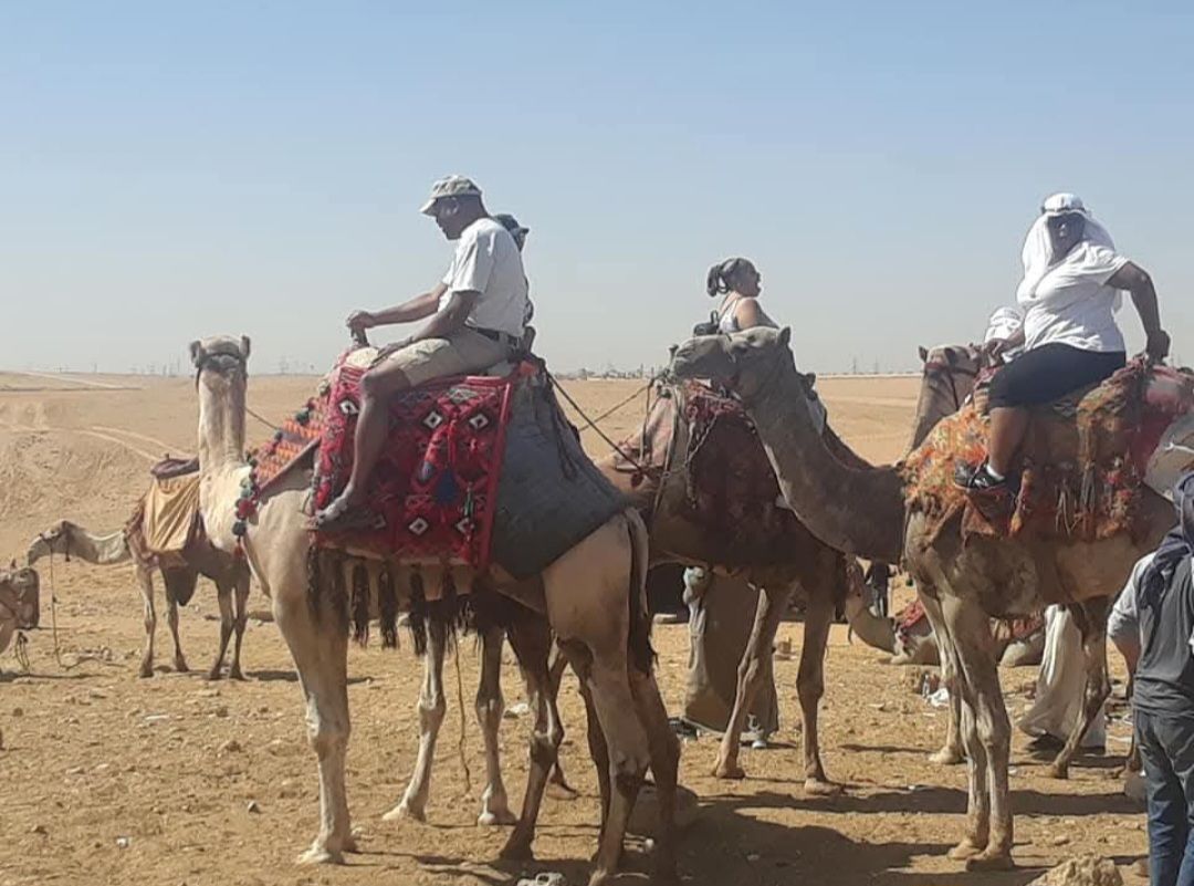 A group of people riding camels in the desert