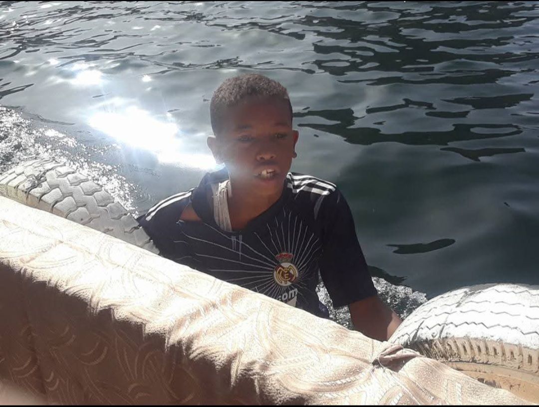 A young boy in a black shirt is swimming in the water