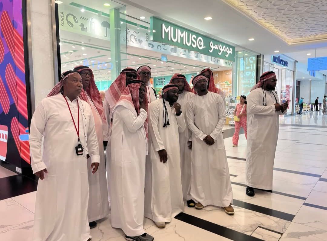 A group of men are standing in front of a store in a mall.
