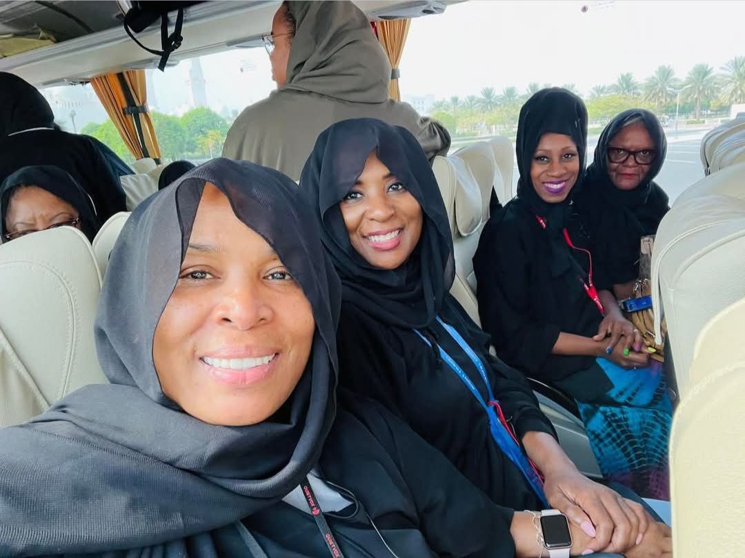 A group of women are sitting on a bus and smiling for the camera.