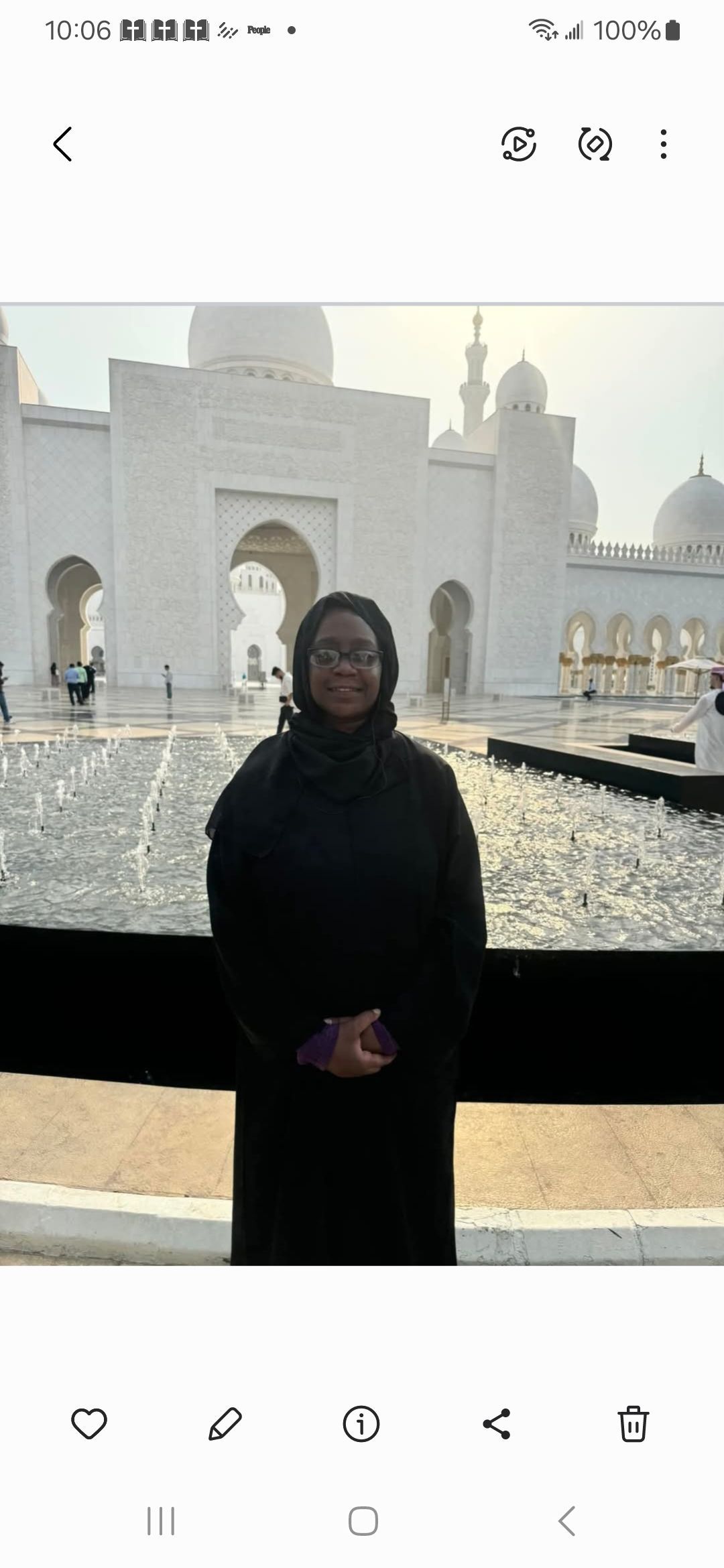 A woman in a black dress is standing in front of a white building.