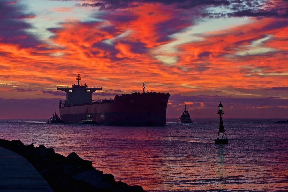 A Large Ship Is Floating On Top Of A Body Of Water At Sunset — East Coast Air In Singleton, NSW