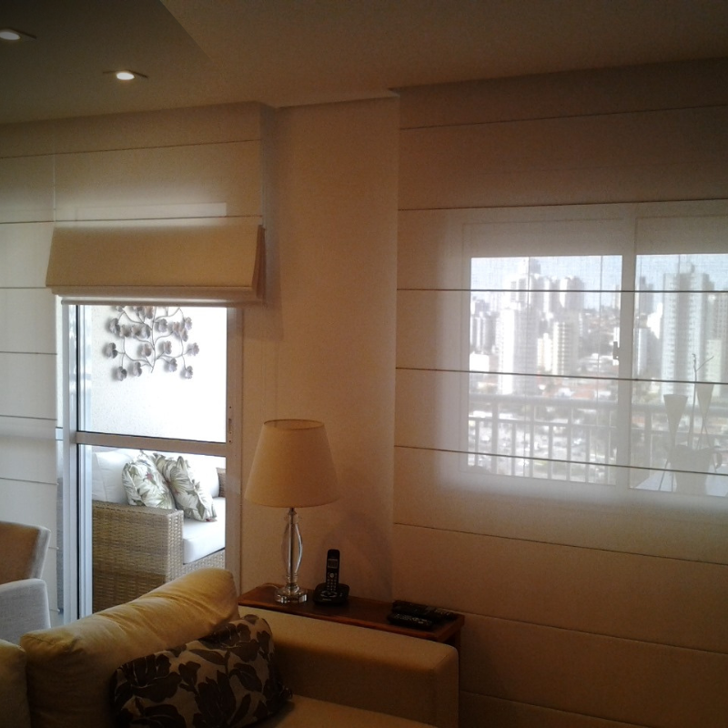 Sala de estar com janela com vista para a cidade. Persianas e móveis brancos, paleta de cores neutras.