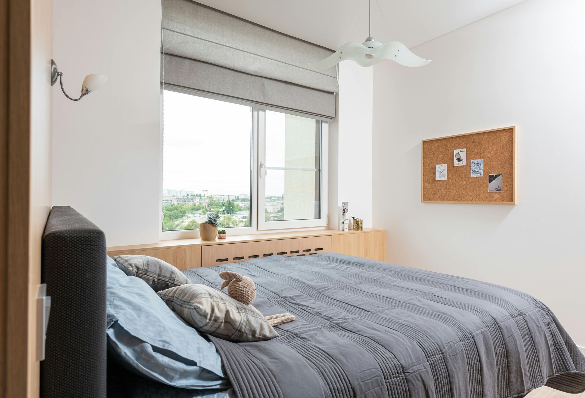 Um quarto com uma cama grande, persianas, um ventilador de teto e uma janela.