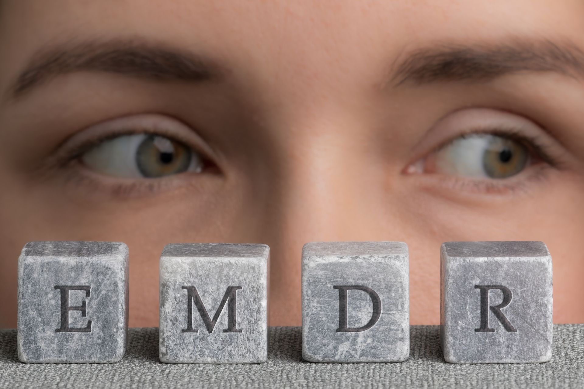 Eyes gazing left, next to stone blocks spelling