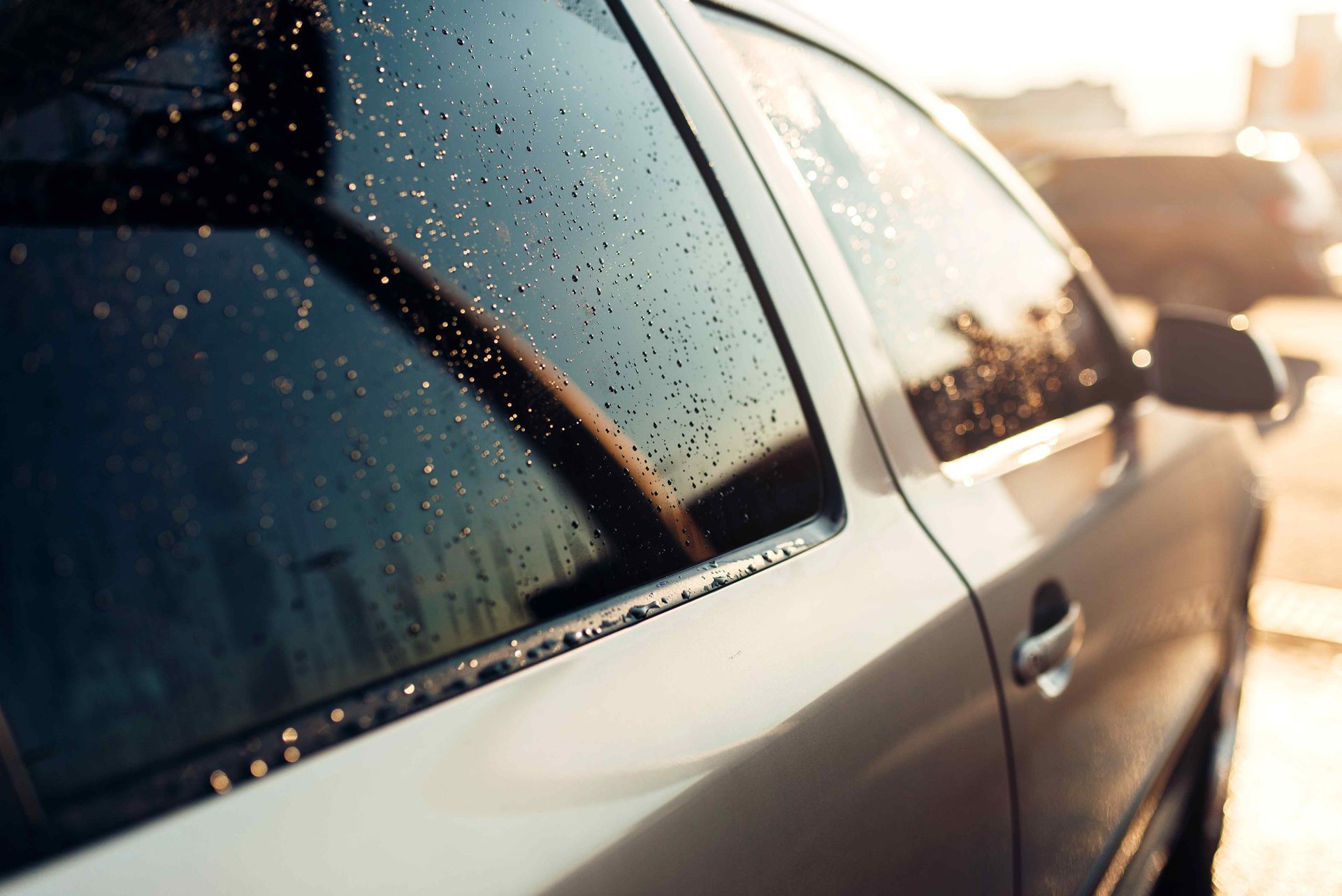 A car outside after raining with rain water on the side of windows