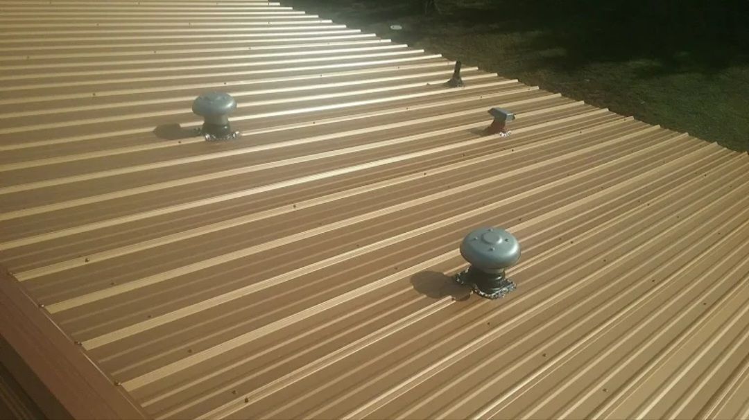 Corrugated metal roof with three small dome vents in sunlight.