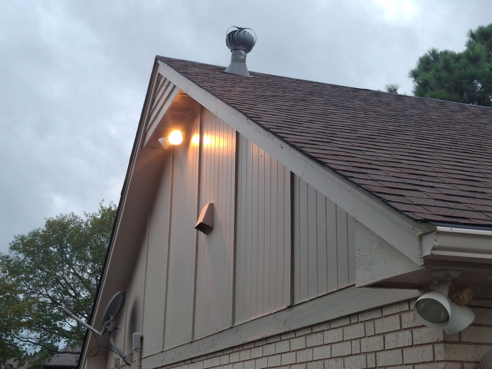 Worker using a yellow power saw to cut roofing shingles on a sloped roof