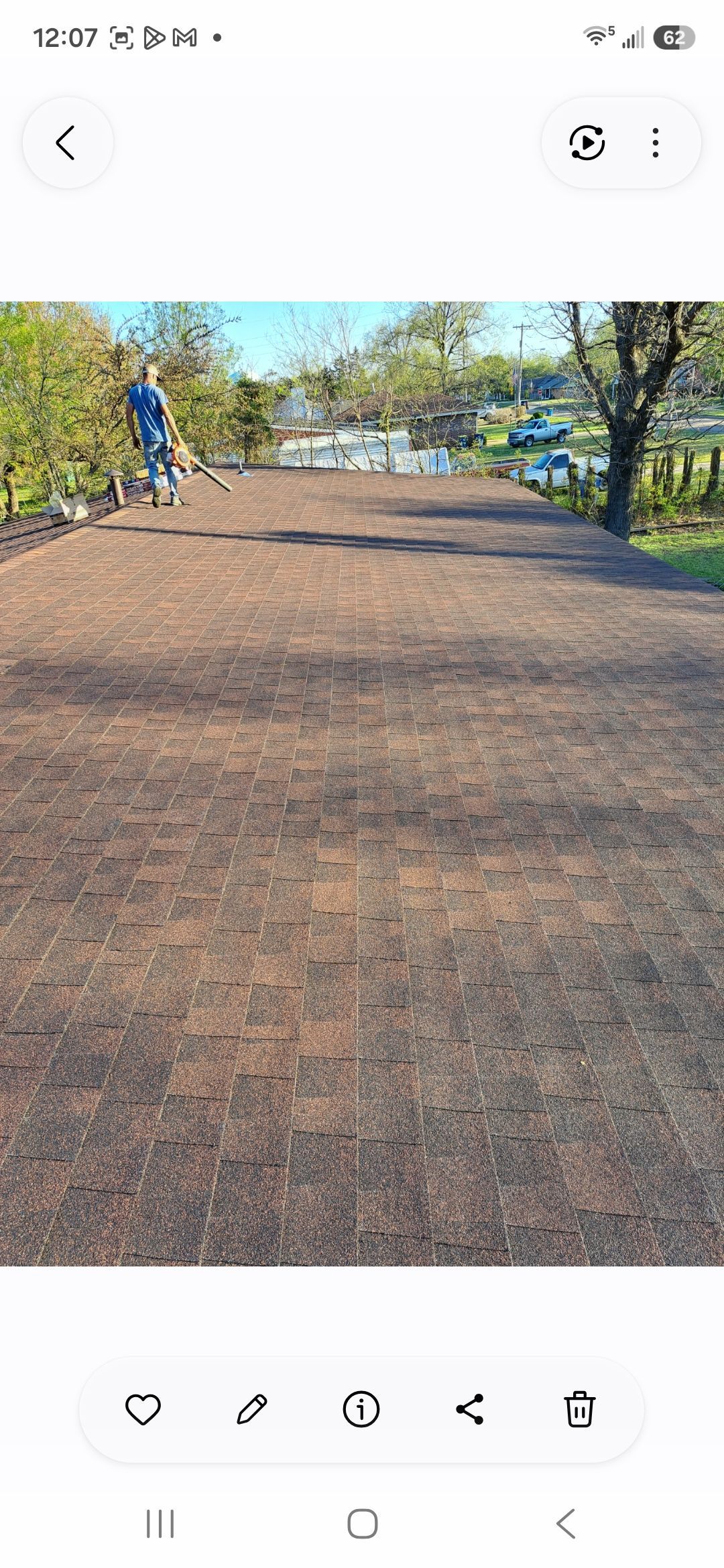 Rooftop with brick pavers and a flat tan surface with trees in the background.