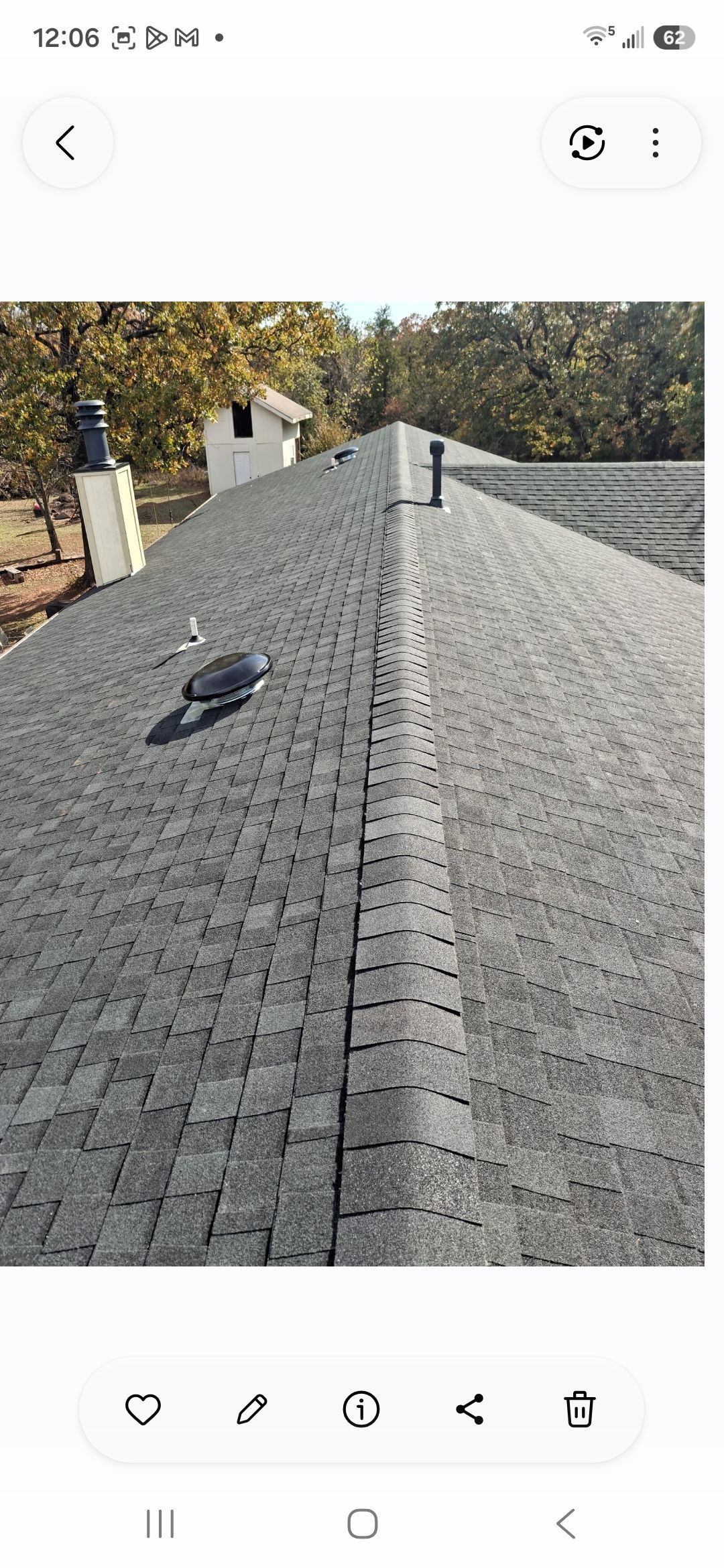 Gravel roof with two vent pipes, a ridge line, and trees in the background.