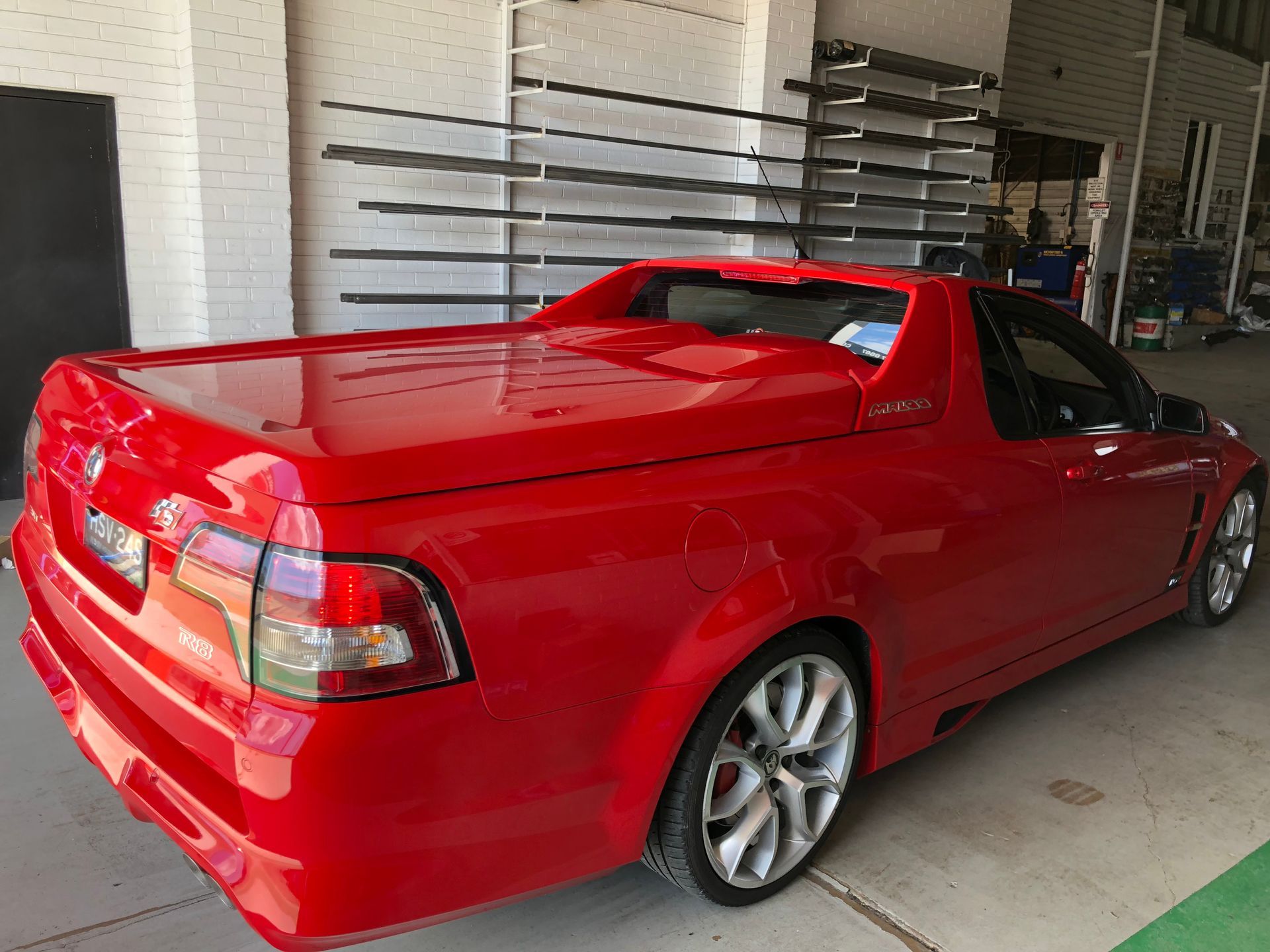 Red utility vehicle with a hard tonneau cover parked in front of a building.